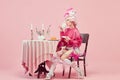 Portrait of elegant princess, queen wearing pink clothes, and wig drinking coffee over pink background. Royalty Royalty Free Stock Photo