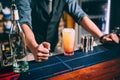 Portrait of elegant and vintage bartender, barman preparing orange based vodka and tequila cocktails