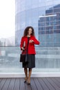 Portrait of a elegant woman, in red suit and black dress, coming on a job, look at the time, have a business meeting.