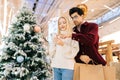 Portrait of elegant young couple looking for store in shopping mall center browsing app on smartphone. Royalty Free Stock Photo