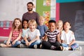 Portrait Of Elementary School Pupils Sitting On Floor In Classroom With Male Teacher Royalty Free Stock Photo