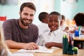 Portrait Of Elementary School Teacher Giving Male Pupil Wearing Uniform One To One Support In Class Royalty Free Stock Photo