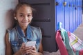 Portrait of elementary schoolgirl listening music through headphones by lockers