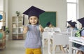 Portrait of happy school girl in square academic cap smiling and giving thumbs up Royalty Free Stock Photo