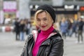 an emotional hipster woman 40-45 years old in a hat on a blurry background of the city and people passing by, Royalty Free Stock Photo