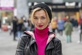 Portrait of an emotional hipster woman 40-45 years old in a hat on a blurry background of the city. Royalty Free Stock Photo