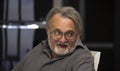 Portrait of an emotional elderly gray-haired man with glasses and a beard on a blurred background. Concept: loneliness in old age