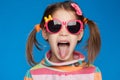 Portrait of an emotional girl of five years old in a striped sweater and in children`s glasses on a blue background Royalty Free Stock Photo