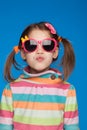 Portrait of an emotional girl of five years old in a striped sweater and in children`s glasses on a blue background Royalty Free Stock Photo