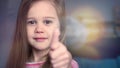 Portrait of emotional little girl show thumb with fantastic bokeh