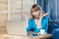 Portrait of emotional shocked young businesswoman in blue blouse are sitting in cafe, reading news and remotely working with Royalty Free Stock Photo