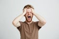 Portrait of emotional upset angry man shouting screaming holding head over white background.