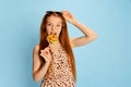 Portrait of emotional young beautiful redhaired girl with long glossy hair tasting lollipop and looking at camera Royalty Free Stock Photo