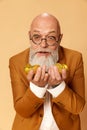 Portrait of emotive bearded, mature, bald man in elegant, classical suit looking at many golden coins in his hands