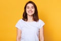 Portrait of emotive good looking caucasian woman laughs while looking directly at camera and standing against yellow background.