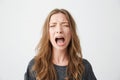 Portrait of emotive young beautiful girl shouting with closed eyes over white background. Royalty Free Stock Photo