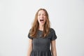 Portrait of emotive young beautiful girl shouting with closed eyes over white background.