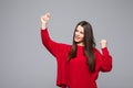 Portrait of energetic woman clenches fists with happiness, has toothy smile, dressed casual red sweater, girl win lottery, Royalty Free Stock Photo