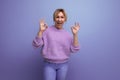 portrait of energetic yawning pleasant blond woman in lavender sweater on purple background with copy space