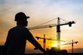 Portrait of engineer silhouette wear a helmet at construction site with crane background and sunset Royalty Free Stock Photo