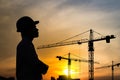 Portrait of engineer silhouette wear a helmet at construction site with crane background and sunset Royalty Free Stock Photo