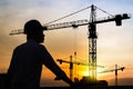 Portrait of engineer silhouette wear a helmet at construction site with crane background and sunset Royalty Free Stock Photo