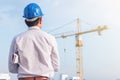 Portrait of engineer wear blue safety helmet and hold the blueprint with commitment on construction site with crane background Royalty Free Stock Photo