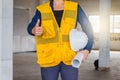 Portrait of engineer wear white safety helmet and holding the blueprint at construction site with crane background Royalty Free Stock Photo