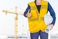 Portrait of engineer wear white safety helmet and holding the blueprint at construction site with crane background Royalty Free Stock Photo