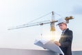 Portrait of engineer wear white safety helmet and verify the blueprint with commitment at construction site with crane background