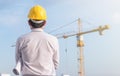 Portrait of engineer wear yellow helmet safety and holding the blueprint at construction site with crane background Royalty Free Stock Photo