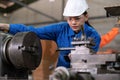 Portrait of engineer worker woman wearing uniform and PPE holding tablet and looking at machine in the factory. Preventive Royalty Free Stock Photo