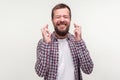 Portrait of enthusiastic bearded man praying for luck with crossed fingers, feeling hopeful. white background Royalty Free Stock Photo