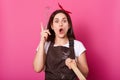 A portrait of enthusiastic energetic baker holding whisk and rolling pin in her hands, looks creative and fun, rise her up, opens Royalty Free Stock Photo