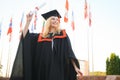 Portrait enthusiastic female college student graduate in cap and gown celebrating, holding diploma.