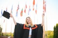 Portrait enthusiastic female college student graduate in cap and gown celebrating, holding diploma.