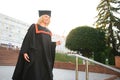 Portrait enthusiastic female college student graduate in cap and gown celebrating, holding diploma.