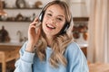 Portrait of european blond girl 20s wearing headphones listening to music at home Royalty Free Stock Photo