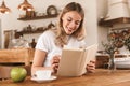 Portrait of european blond woman reading book and drinking coffee while sitting in cozy cafe indoor Royalty Free Stock Photo