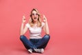 Portrait of european blond woman 20s wearing vintage sunglasses laughing while sitting on floor with legs crossed Royalty Free Stock Photo