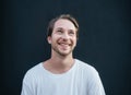 Portrait of european happy man in white t-shirt at dark wall