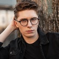 Portrait european serious young man with brown hair with clean healthy skin in fashionable glasses in black stylish jacket near Royalty Free Stock Photo