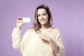 Portrait of european young smiling business woman holding credit card. isolated on violet background