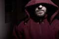 Portrait of an evil bearded man in a hoodie in the dark. Male criminal hides his eyes under the hood. Royalty Free Stock Photo