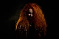 Portrait of an evil red-haired witch conjures in the dark. Royalty Free Stock Photo