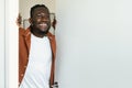 Portrait of excited african american man standing in doorway of his apartment, looking out through slightly open door Royalty Free Stock Photo