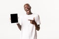 Portrait of excited and amazed african-american blond guy, looking impressed and pointing finger at digital tablet