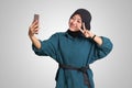 Portrait of excited Asian muslim woman with hijab holding mobile phone while in video calling with her hand gesture saying hi. Royalty Free Stock Photo