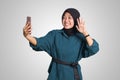 Portrait of excited Asian muslim woman with hijab holding mobile phone while in video calling with her hand gesture saying hi. Royalty Free Stock Photo