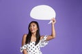 Portrait of an excited asian woman in dress holding blank speech bubble